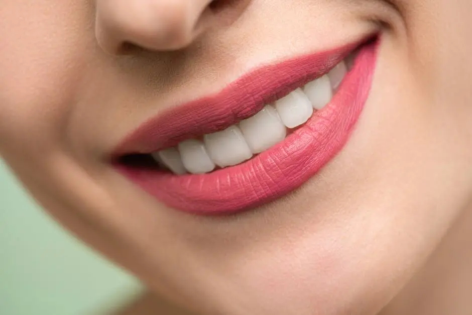 Vivid close-up image of a woman’s smile showcasing red lipstick and white teeth on a light background.